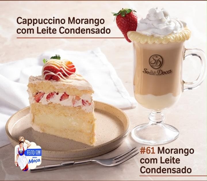 Cappuccino com borda branca e morango ao lado de fatia de bolo de morango com leite condensado.